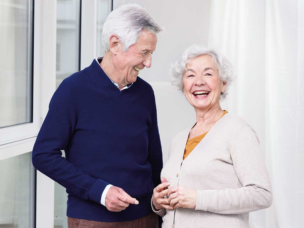 Vanhempi mies ja nainen seisovat rinnakkain hymyillen